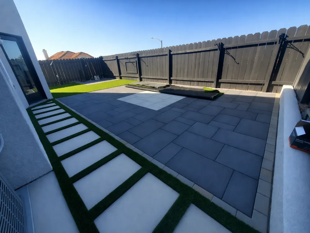 Charcoal paver patio with artificial turf ribbons and a stepping path